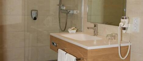 Un baño moderno con ducha, lavabo con espejo e inodoro.