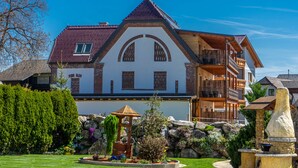 A large, two-story house with a steeply pitched roof, a balcony, and a well-maintained garden with a gazebo. - Hotel Restaurant Perschler (Fohnsdorf)