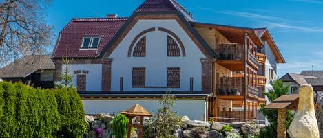 A large, two-story house with a steeply pitched roof, a balcony, and a well-maintained garden with a gazebo.