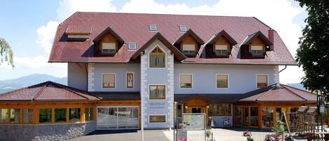A large, multi-story building with a steeply pitched roof, multiple windows, and a sign reading "Peschlitzer".