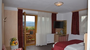 A hotel room with a bed, a television, a desk, a chair, and a view of the outdoors. - Hotel Restaurant Perschler (Fohnsdorf)