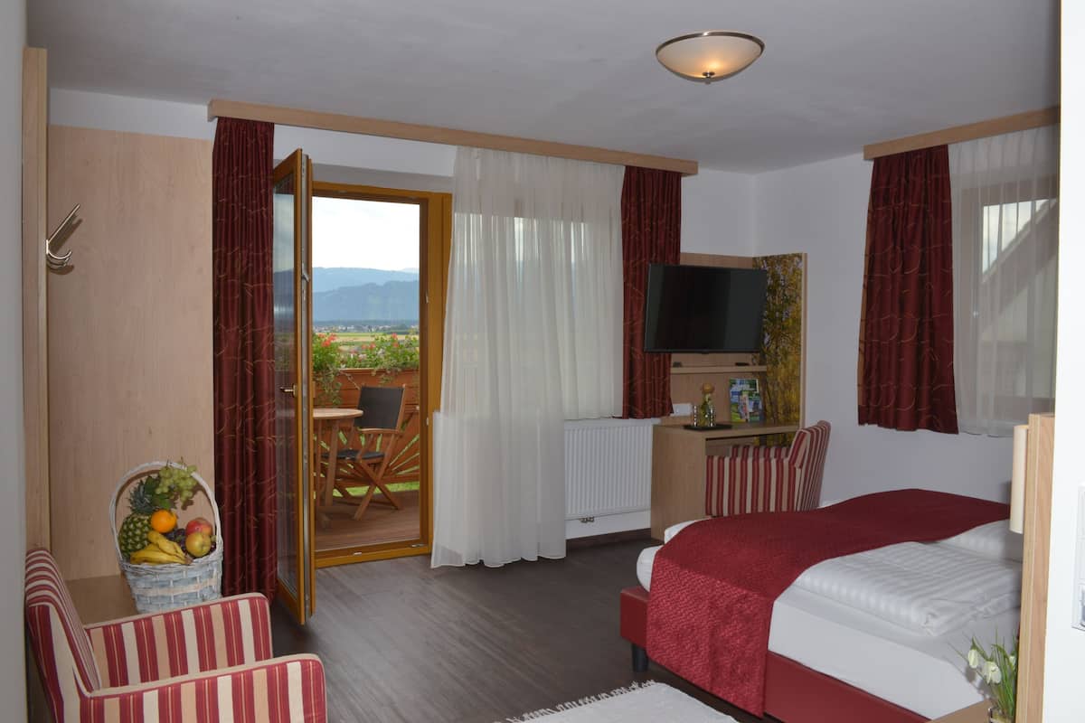 A hotel room with a bed, a television, a desk, a chair, and a view of the outdoors.