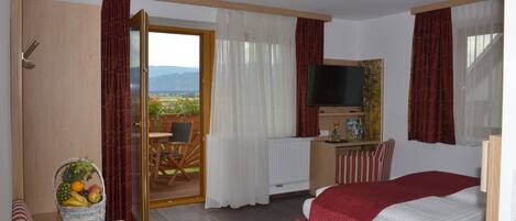 Habitación de hotel con cama, televisión, escritorio, una silla y vistas al exterior.