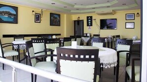 Un restaurante con varias mesas y sillas, un techo con iluminación empotrada y cuadros en las paredes.