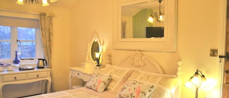 Une chambre à coucher comprenant un lit, une commode, une table de chevet, un miroir et une fenêtre avec des rideaux.