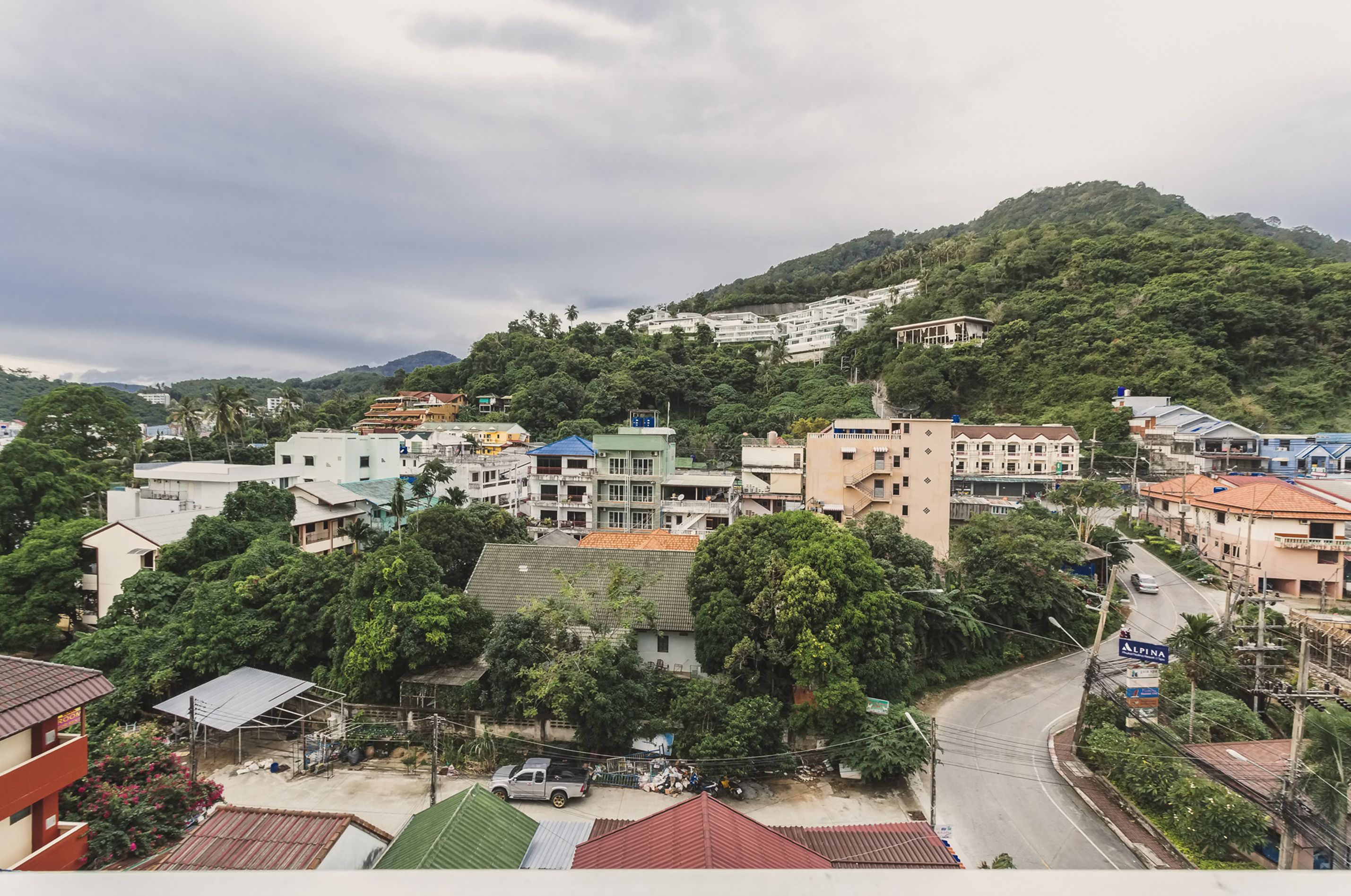 A residential area with houses, a winding road, and a hill in the background.