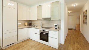 Una cocina moderna con armarios blancos, horno empotrado y una encimera con cafetera.
