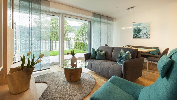 Una sala moderna con sofá, sillones, una mesa de centro de vidrio y un comedor.