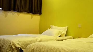 Une chambre avec deux lits, une fenêtre avec des rideaux et un interrupteur sur le mur.