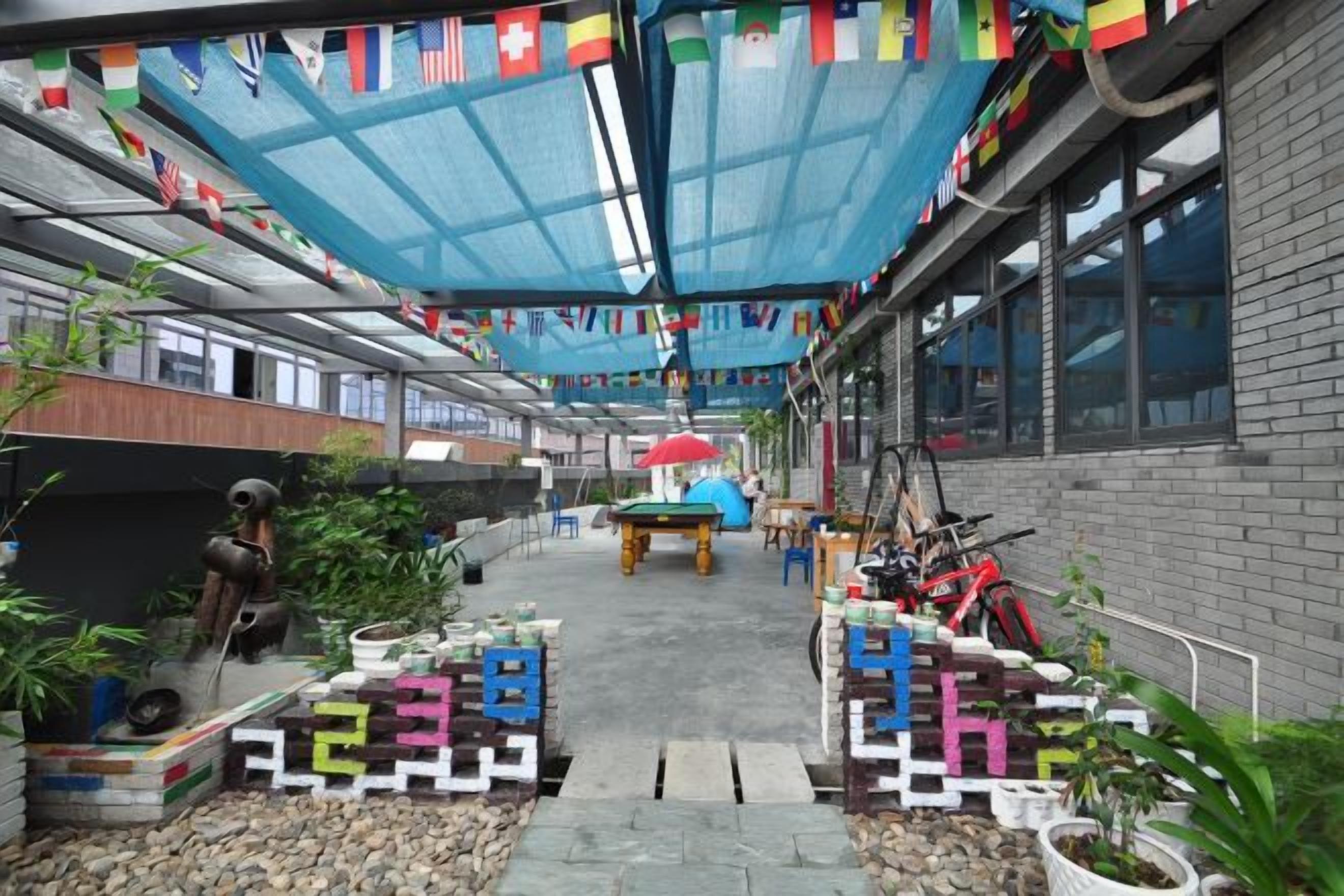 A covered outdoor area with a table, chairs, and potted plants.