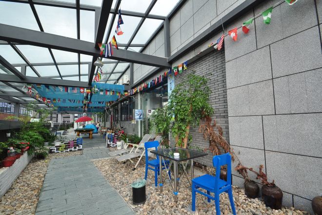 Un espace extérieur abrité, aménagé avec des sièges, des plantes en pot et une structure de plafond en verre.