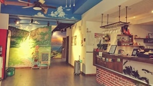 A hotel lobby with a mural, a reception desk, and a ceiling fan. - Ningbo 238 International Youth Hostel (Ningbo)