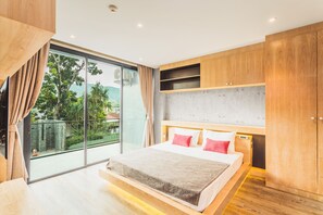 A modern bedroom with a large bed, wooden headboard, and a sliding glass door leading to a balcony. - Condo in Nai Harn in ReLife 15-122-211 (Rawai)