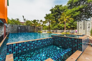 Una piscina al aire libre, sombrillas, sillones reclinables de piscina