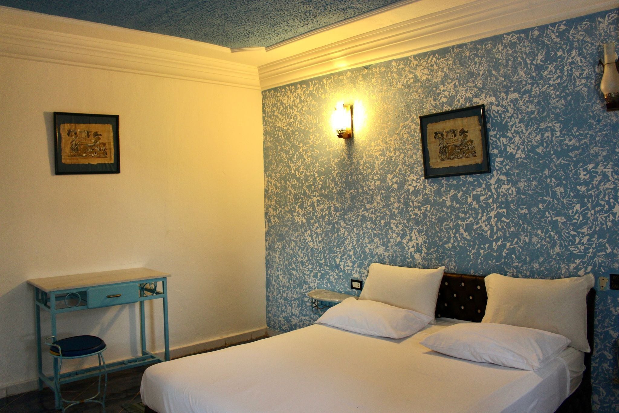 A bedroom with a bed, a desk, and two wall-mounted light fixtures.