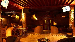 A lobby with a wooden floor, a reception desk, and a large mirror. - Hotel Donia (Hammam Chatt)