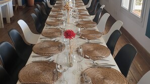 A long dining table set with woven placemats, clear glassware, and a central floral arrangement. - WaWa Tarifa (Tarifa)