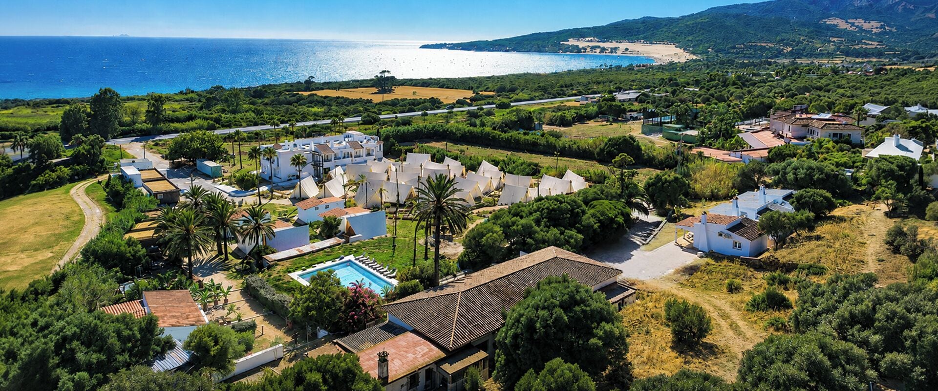 A coastal resort with villas, a swimming pool, and a view of the sea.