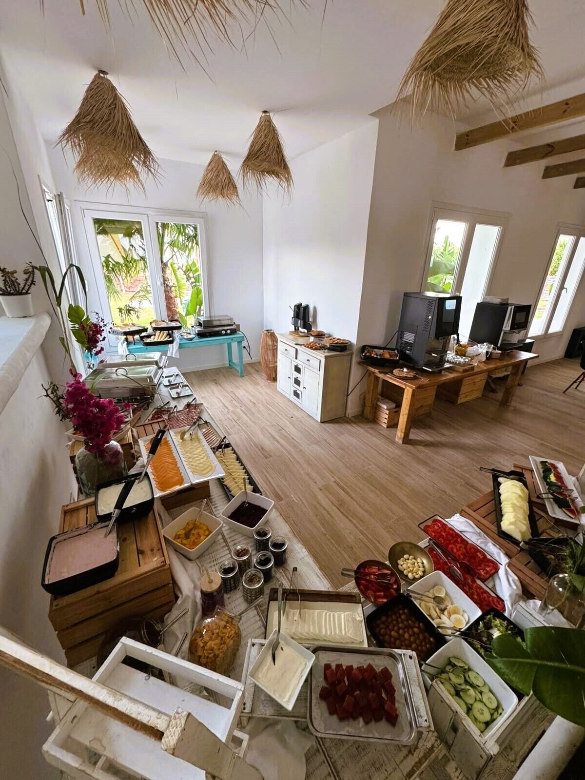 Een ruime kamer met een buffetopstelling, een televisie en een raam met uitzicht op groen.
