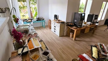 Een ruime kamer met een buffetopstelling, een televisie en een raam met uitzicht op groen.