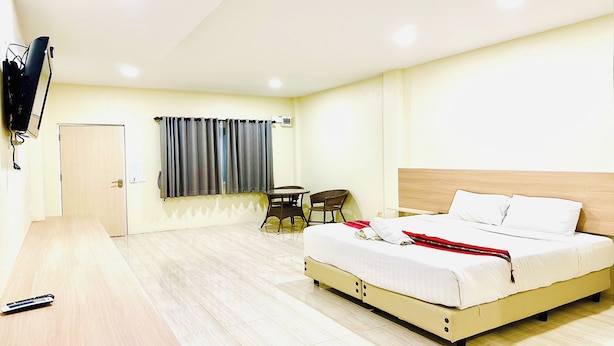 Una habitación de hotel con cama, escritorio, silla, televisión y ventana con cortinas.