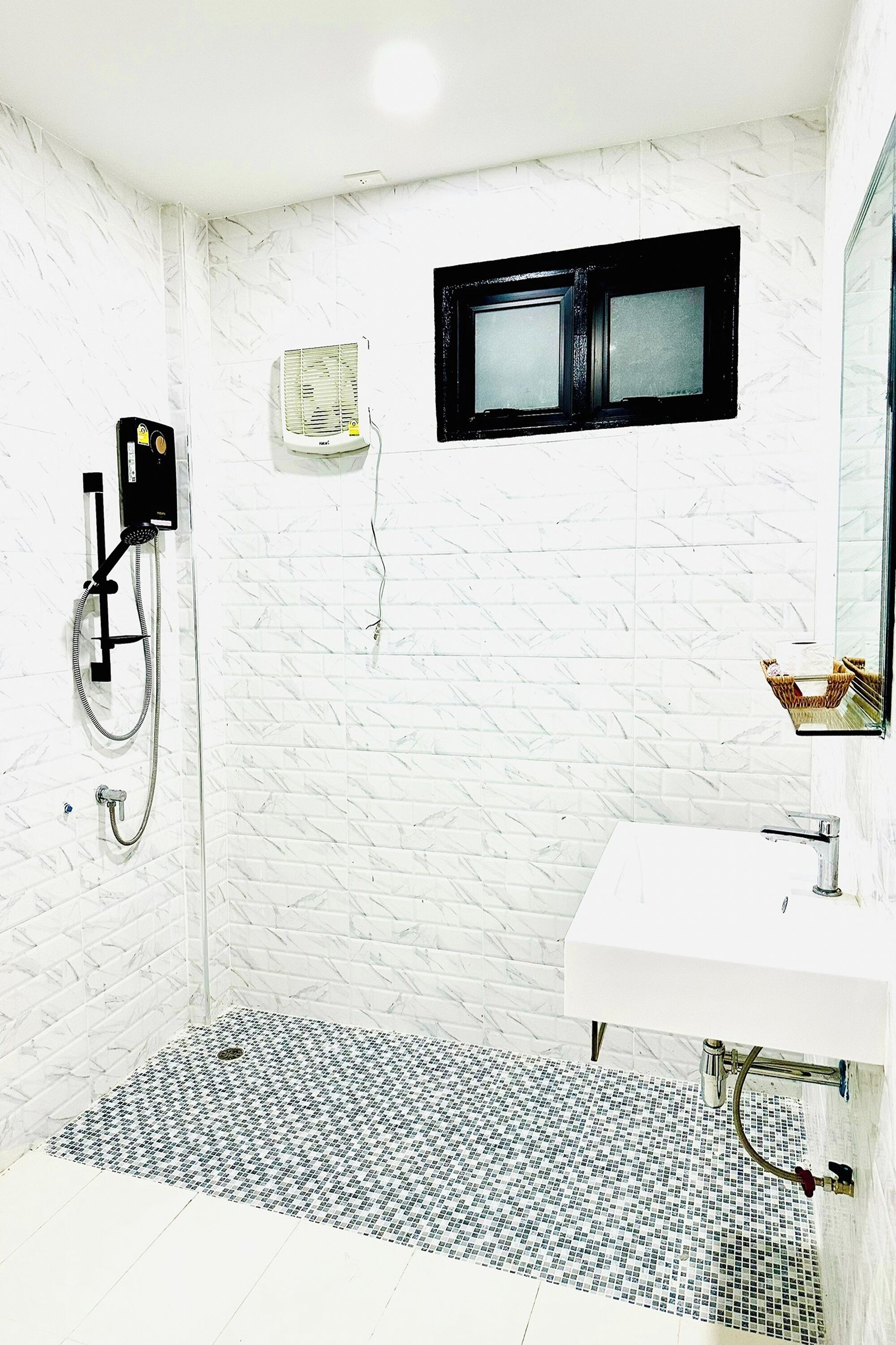 A bathroom with a white tiled shower area, a white sink, and a small mirror above the sink.