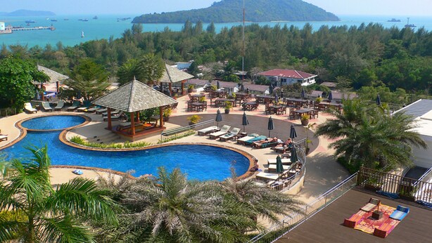 A resort with a large swimming pool, outdoor seating areas, and a view of the sea and a distant island. - Condo in Panwa in Bel Air - Unit C204 (Wichit)