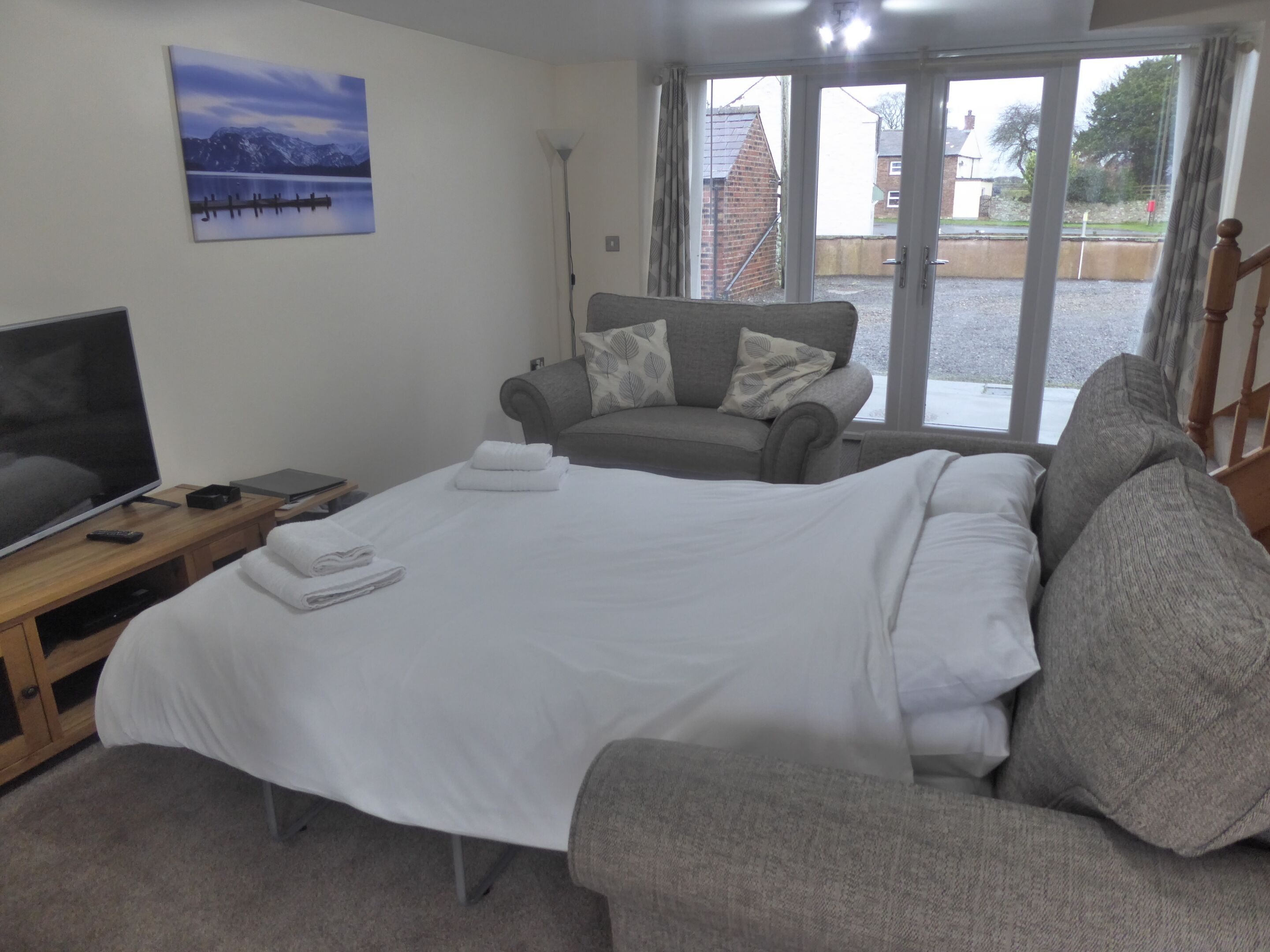 Ein Schlafzimmer mit Bett, einer Couch, einem Fernseher und einem Bild an der Wand.