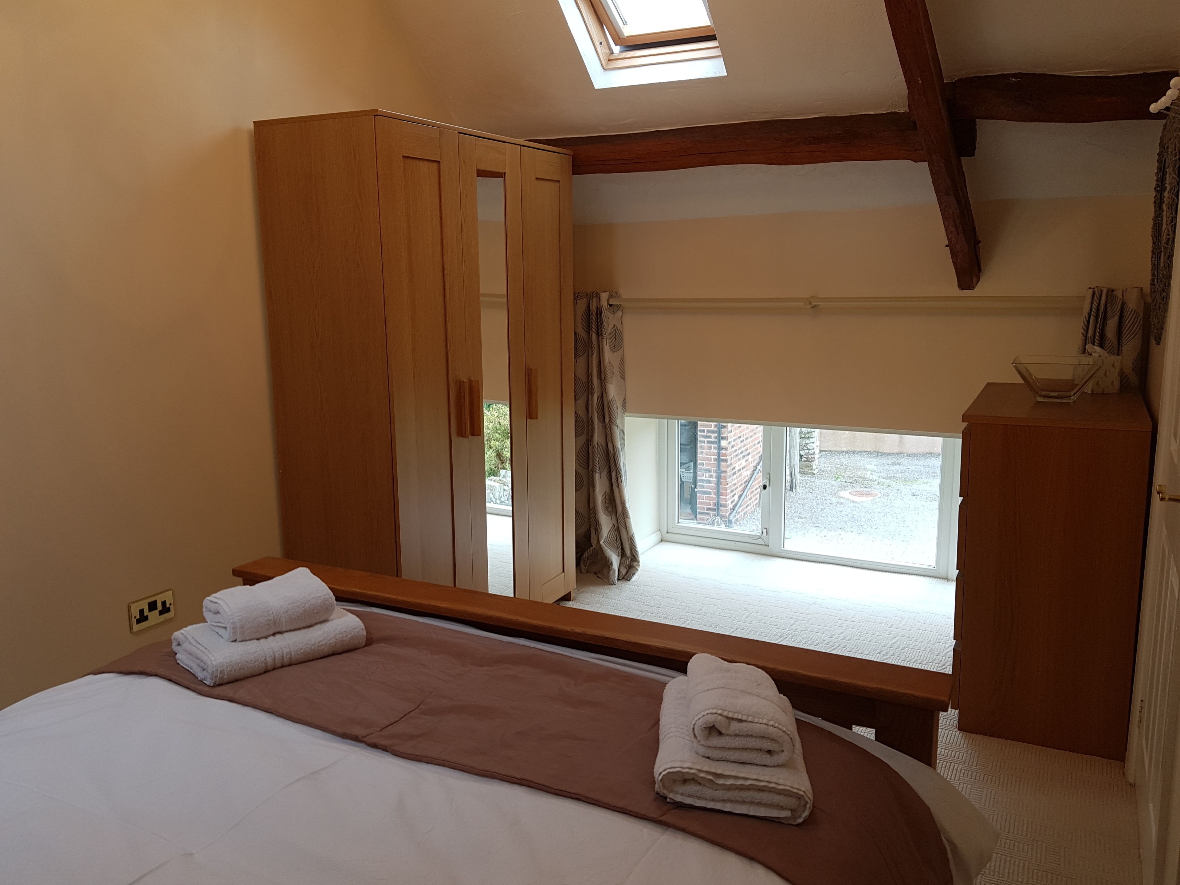 A bedroom with a bed, a wardrobe, a window, and a skylight.