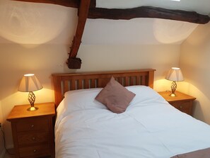 A bedroom with a wooden bed, two bedside tables with lamps, and a wooden nightstand with drawers. - Green View Lodges (Carlisle)
