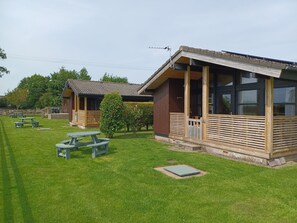 A campsite with two wooden cabins, picnic tables, and a well-maintained lawn. - Green View Lodges (Carlisle)