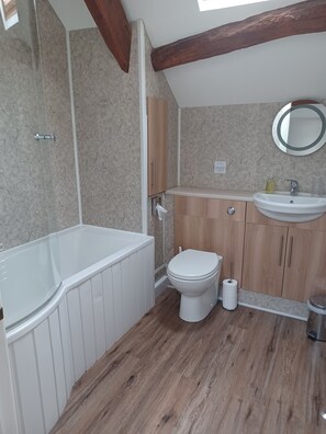 A modern bathroom with a bathtub, toilet, and sink. - Green View Lodges (Carlisle)