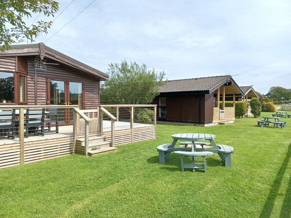A wooden cabin with a deck and outdoor seating area. - Green View Lodges (Carlisle)