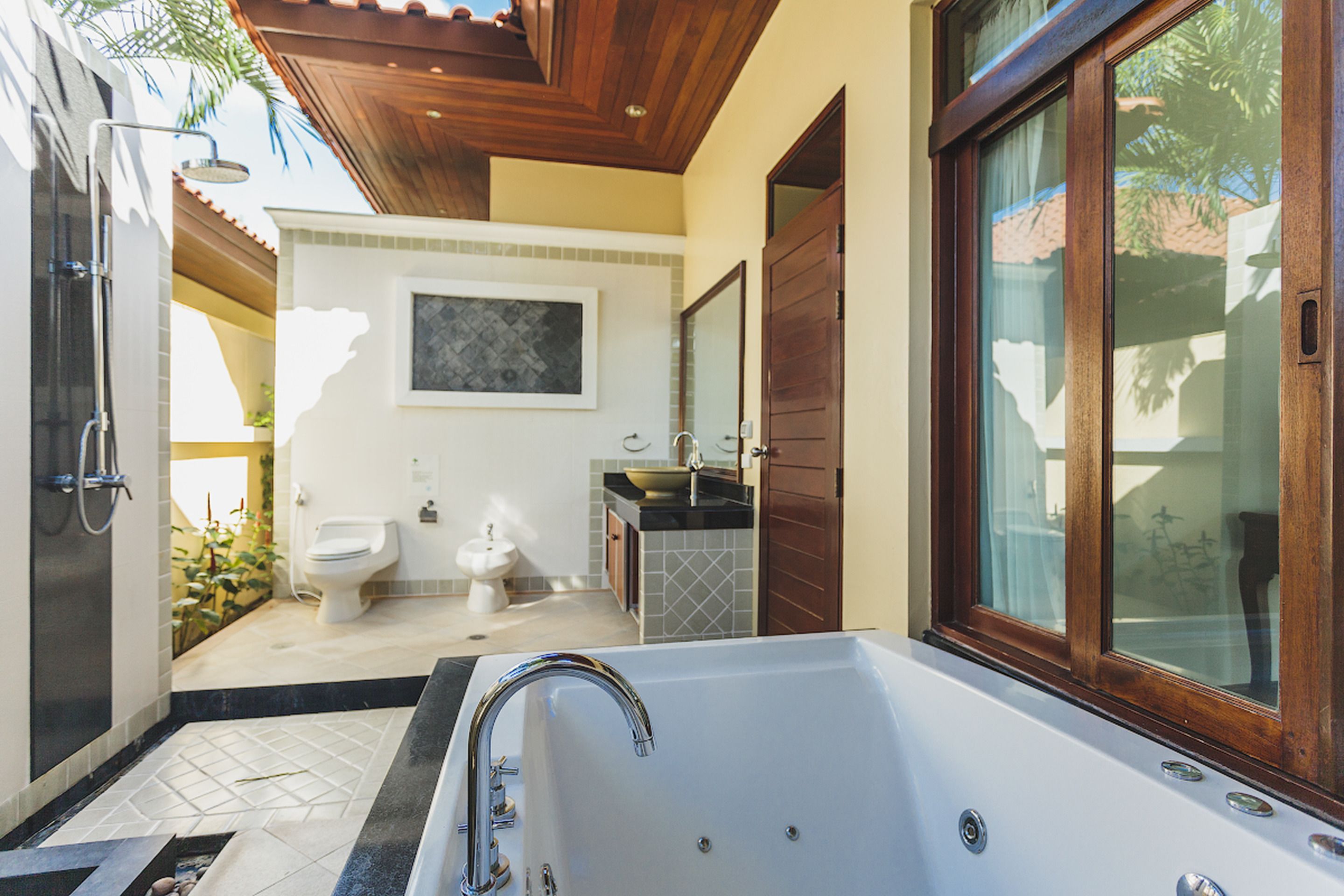 A modern bathroom with a large bathtub, a toilet, and a sink.