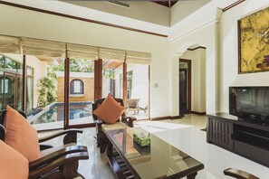 Amplia sala de estar con un gran ventanal, una piscina y un televisor.