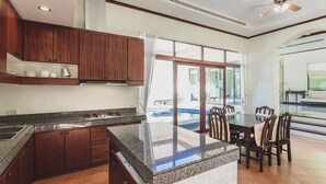 A spacious kitchen with granite countertops, wooden cabinets, and a large dining area with a table and chairs.