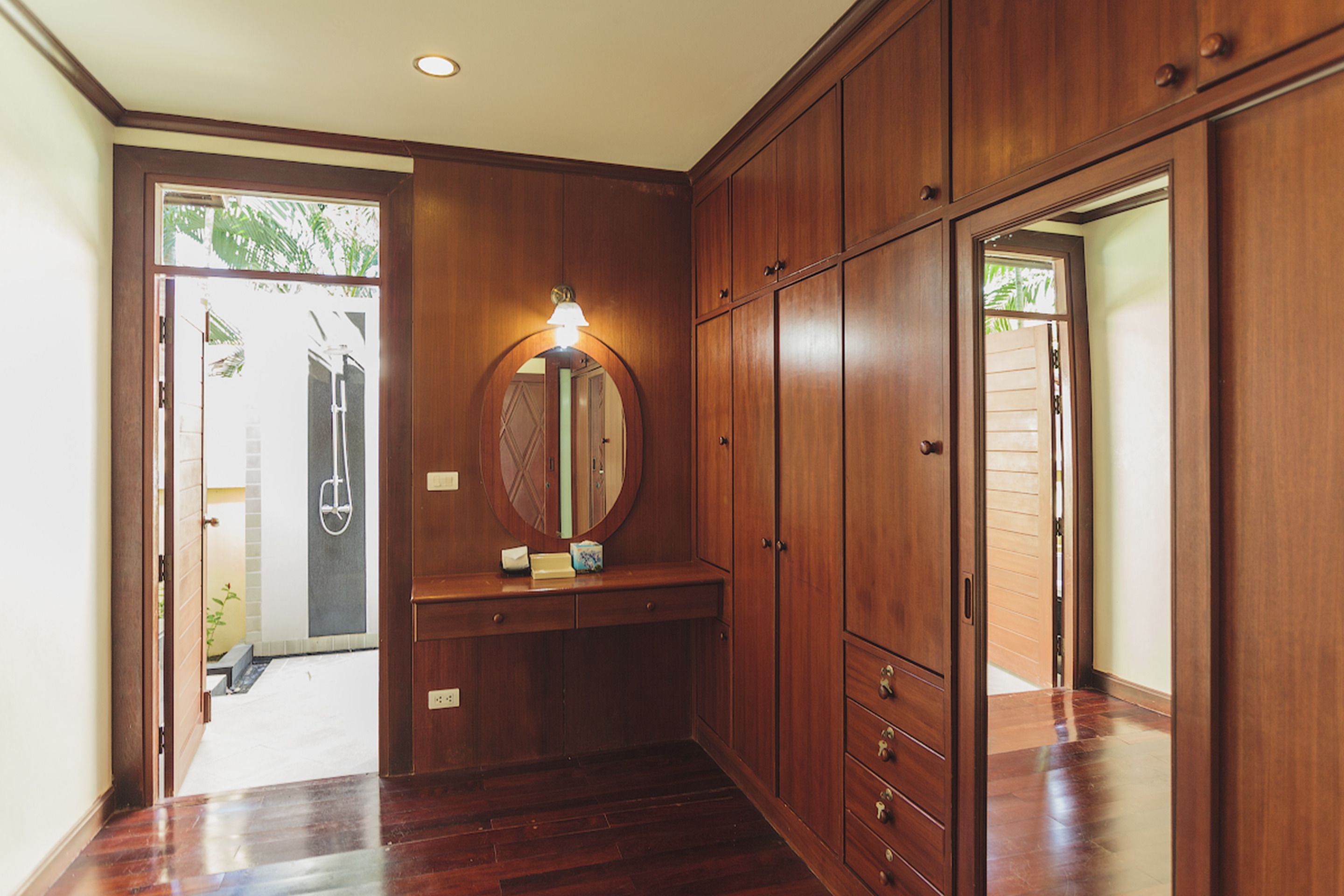 A hallway with wooden cabinets, a mirror, and a bench.
