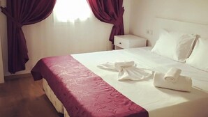 A hotel room with a bed, a nightstand, and a window with curtains. - Cohiba Hotel (Bodrum)