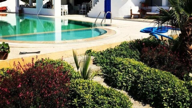 A modern pool area with a clear pool, a covered seating area, and a staircase leading to an upper level. - Cohiba Hotel (Bodrum)