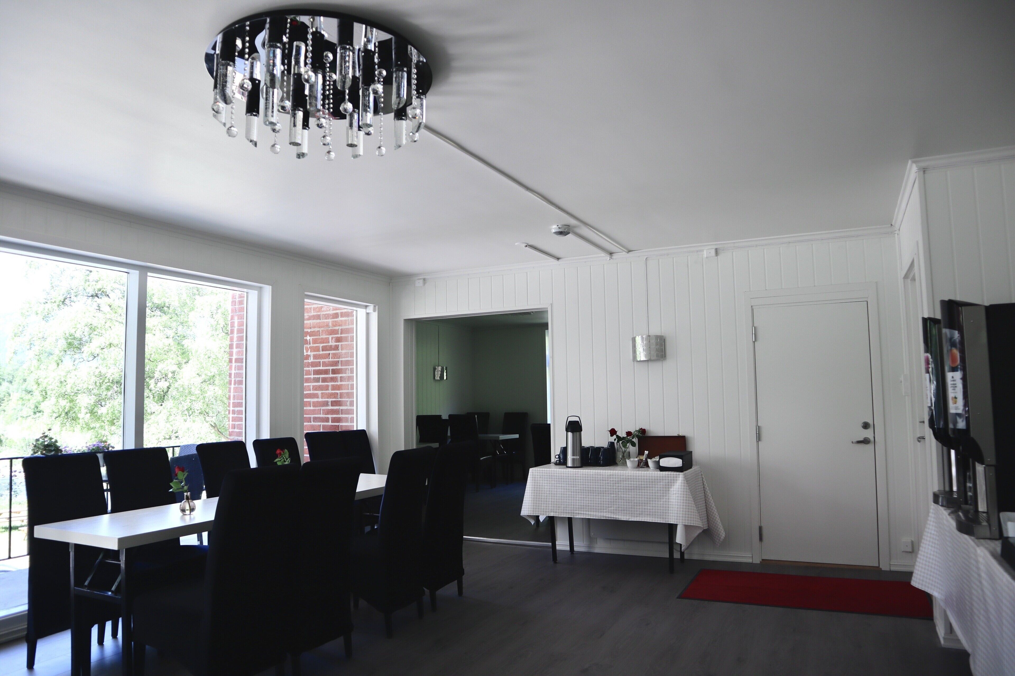 A dining area with a chandelier, tables, chairs, and a view of the outdoors.