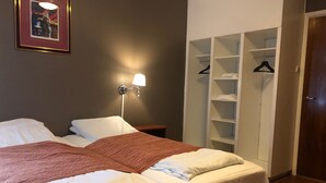 A hotel room with a bed, a nightstand, a lamp, and a wardrobe. - Rjukan Gjestehus (Tinn)