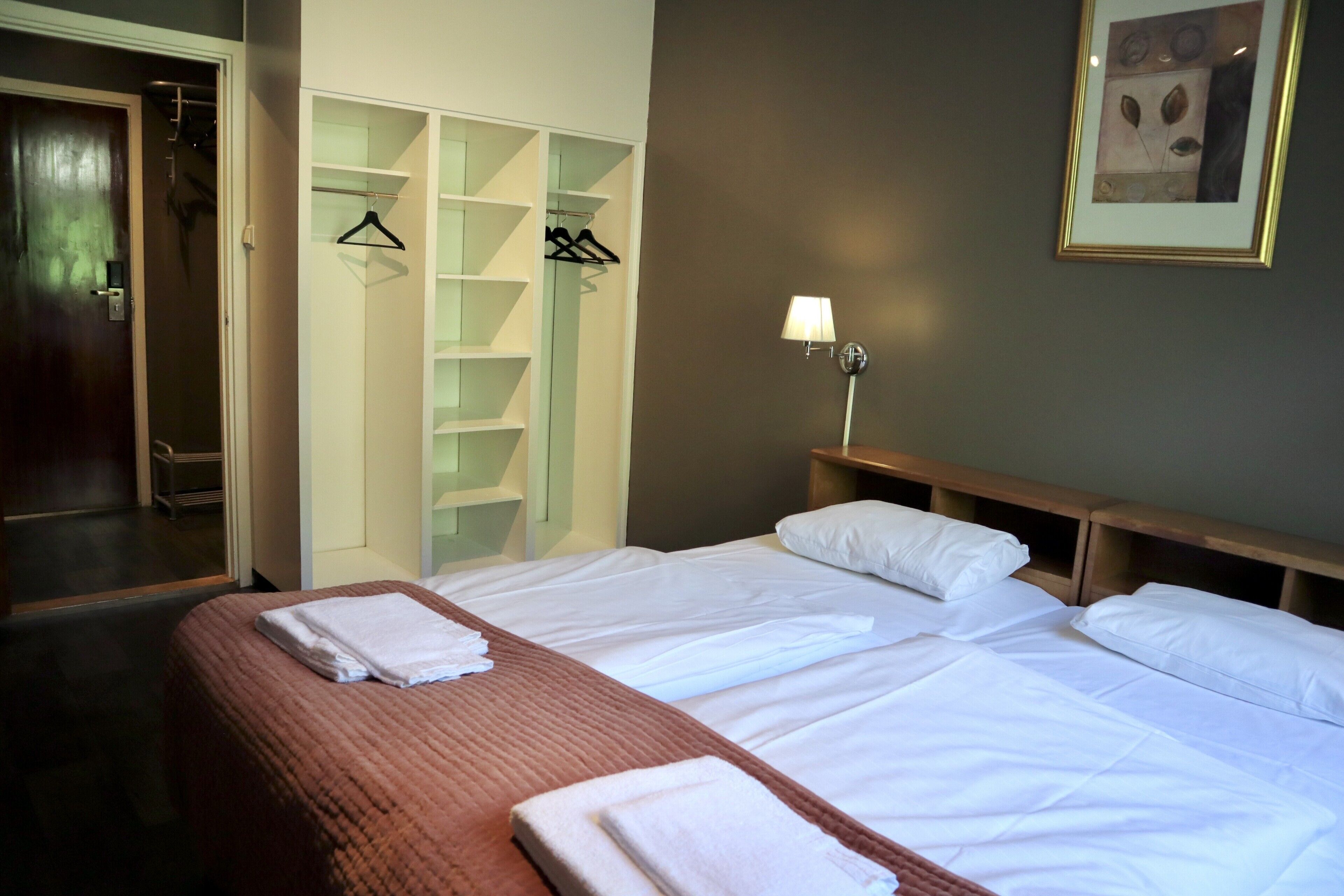 Una habitación de hotel con una cama, un armario y una lámpara fijada a la pared.
