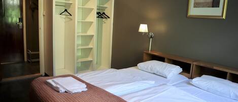 Una habitación de hotel con una cama, un armario y una lámpara fijada a la pared.