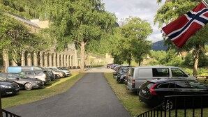 A parking area with cars and a flag. - Rjukan Gjestehus (Tinn)