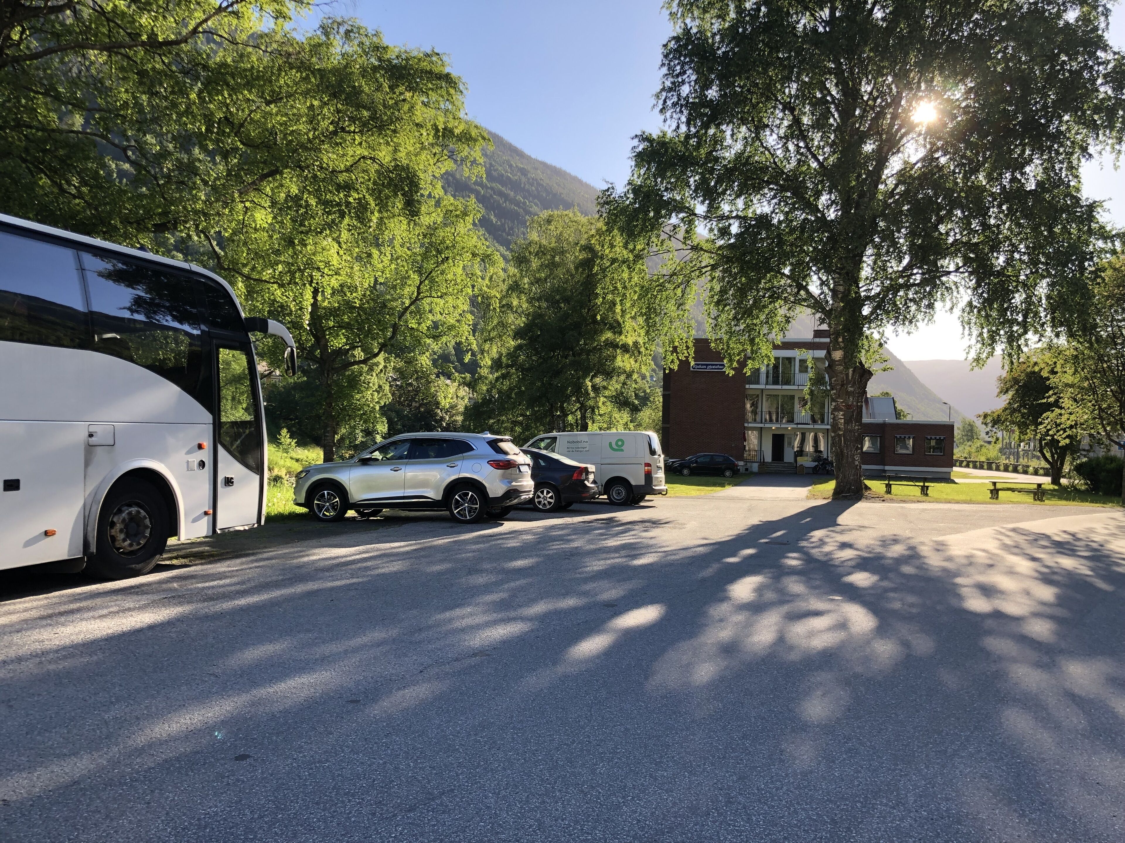 A parking area with a bus, a white SUV, and a delivery van.