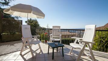 A patio with two white chairs, a table, and a large umbrella.