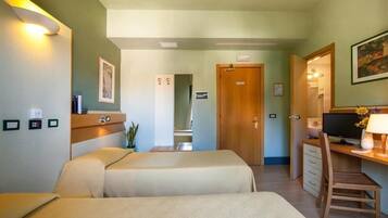 A hotel room with two beds, a desk with a computer, a chair, and a TV.