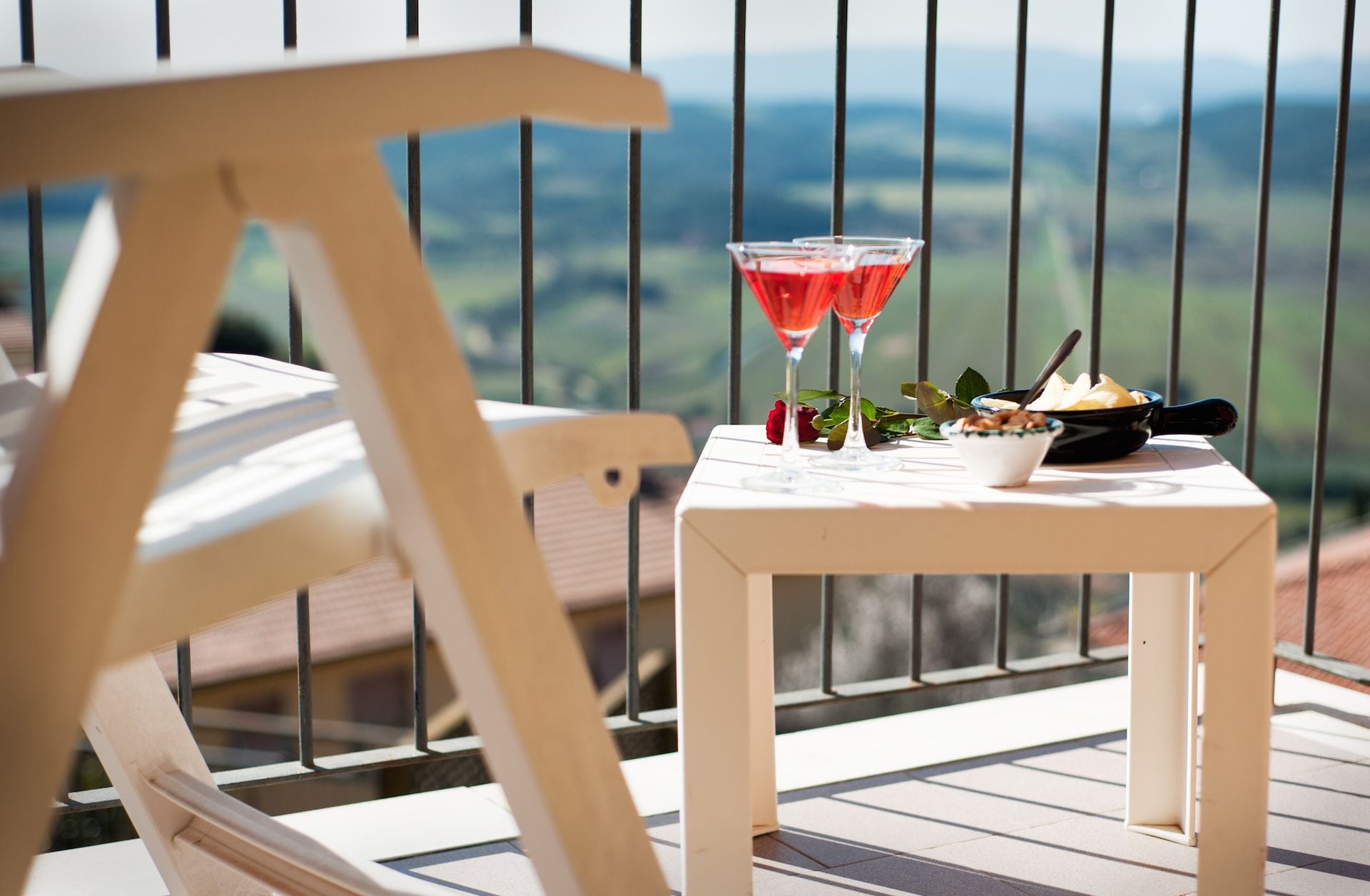 A wooden chair and a small table with a view of the countryside.