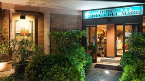 The exterior of Hotel Ducca del Mare with a well-lit entrance, a visible sign, and potted plants around the entrance. - Hotel Duca Del Mare (Massa Marittima)