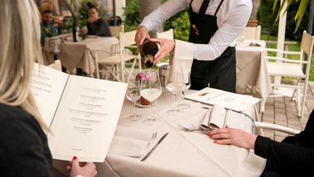 A waiter pouring wine into a glass at an outdoor restaurant. - Hotel Duca Del Mare (Massa Marittima)